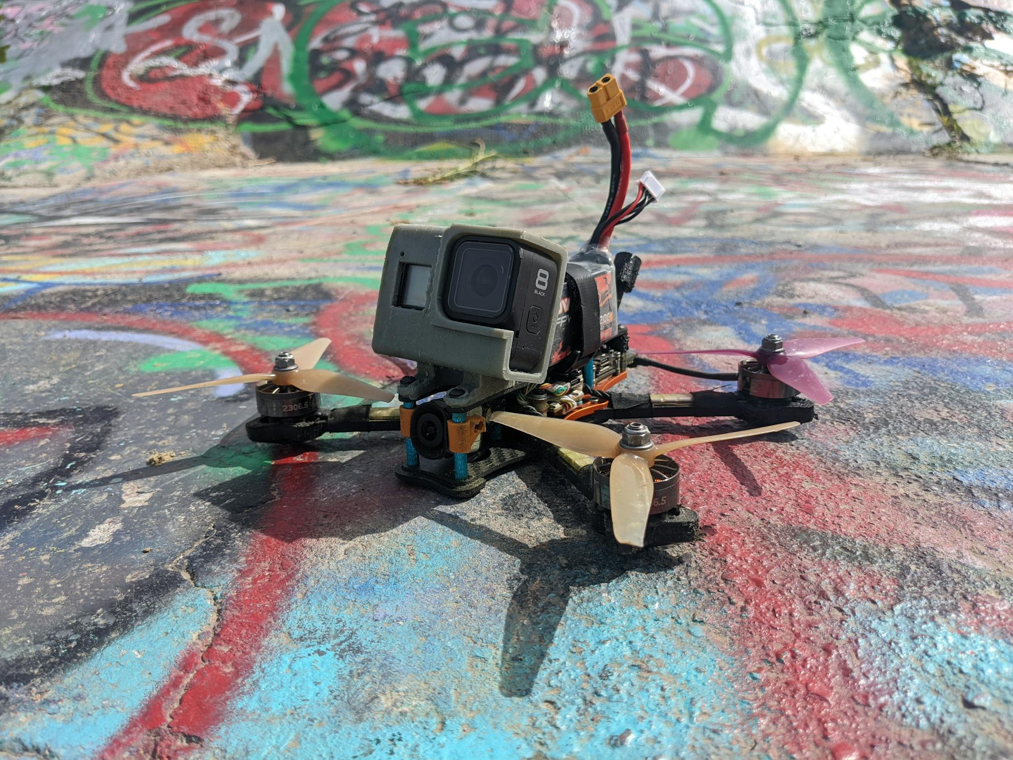 Close-up of an FPV racing drone with a camera on colorful graffiti background outdoors.